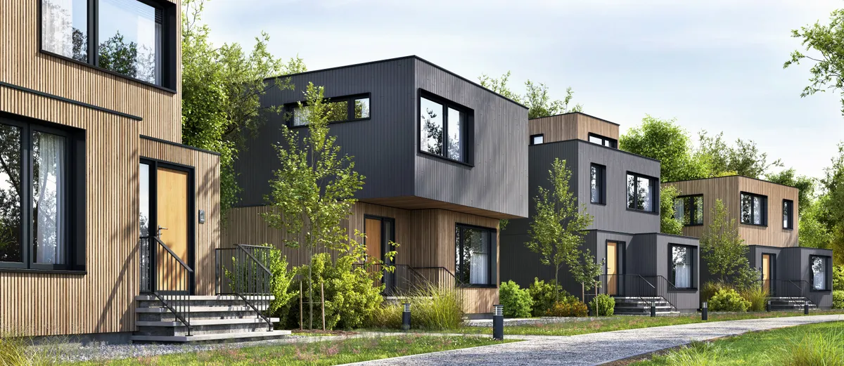 Row of modular container homes clad in vertical timber and dark panels along a landscaped path
