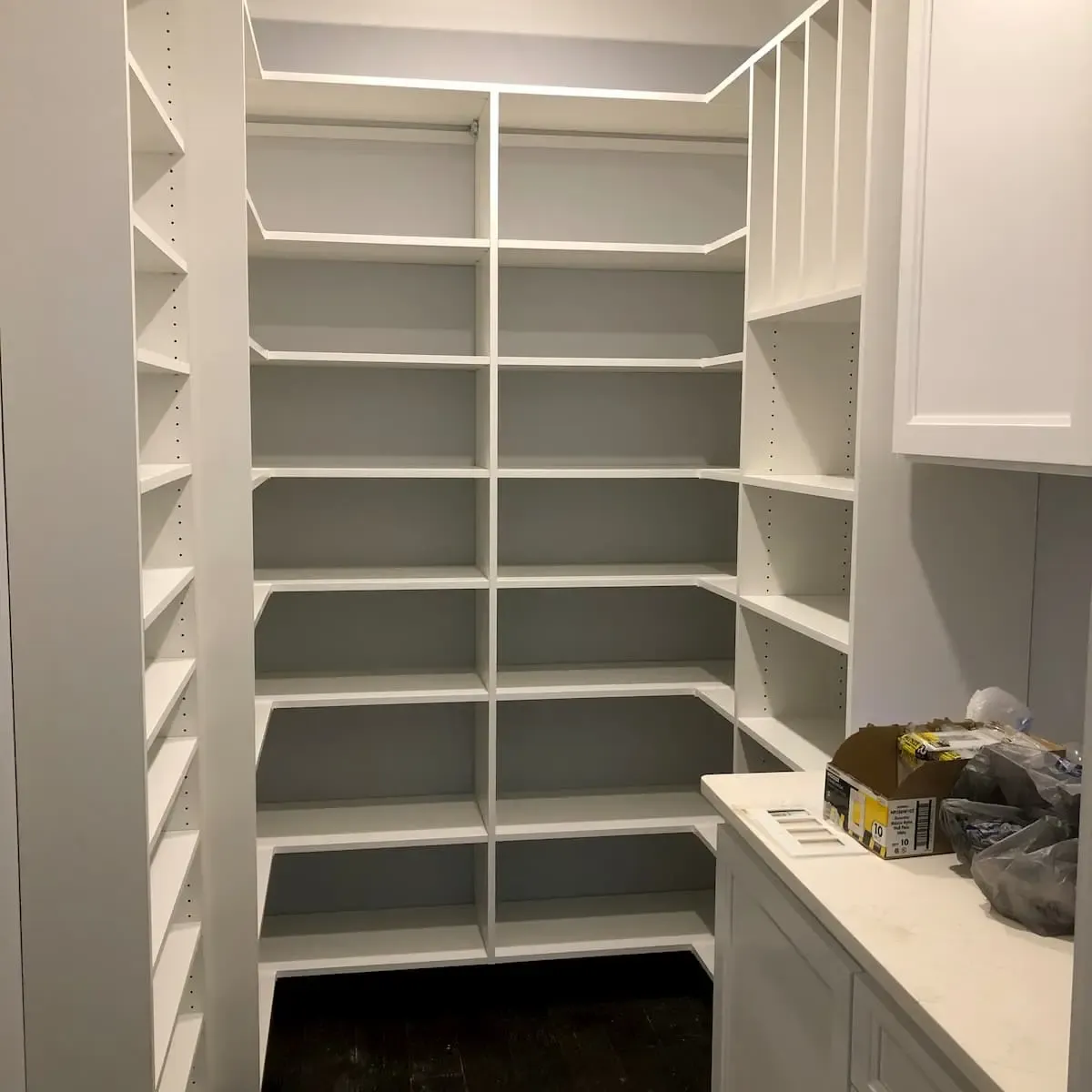 Corner pantry with floor-to-ceiling adjustable shelving and a built-in spice rack beside a marble countertop
