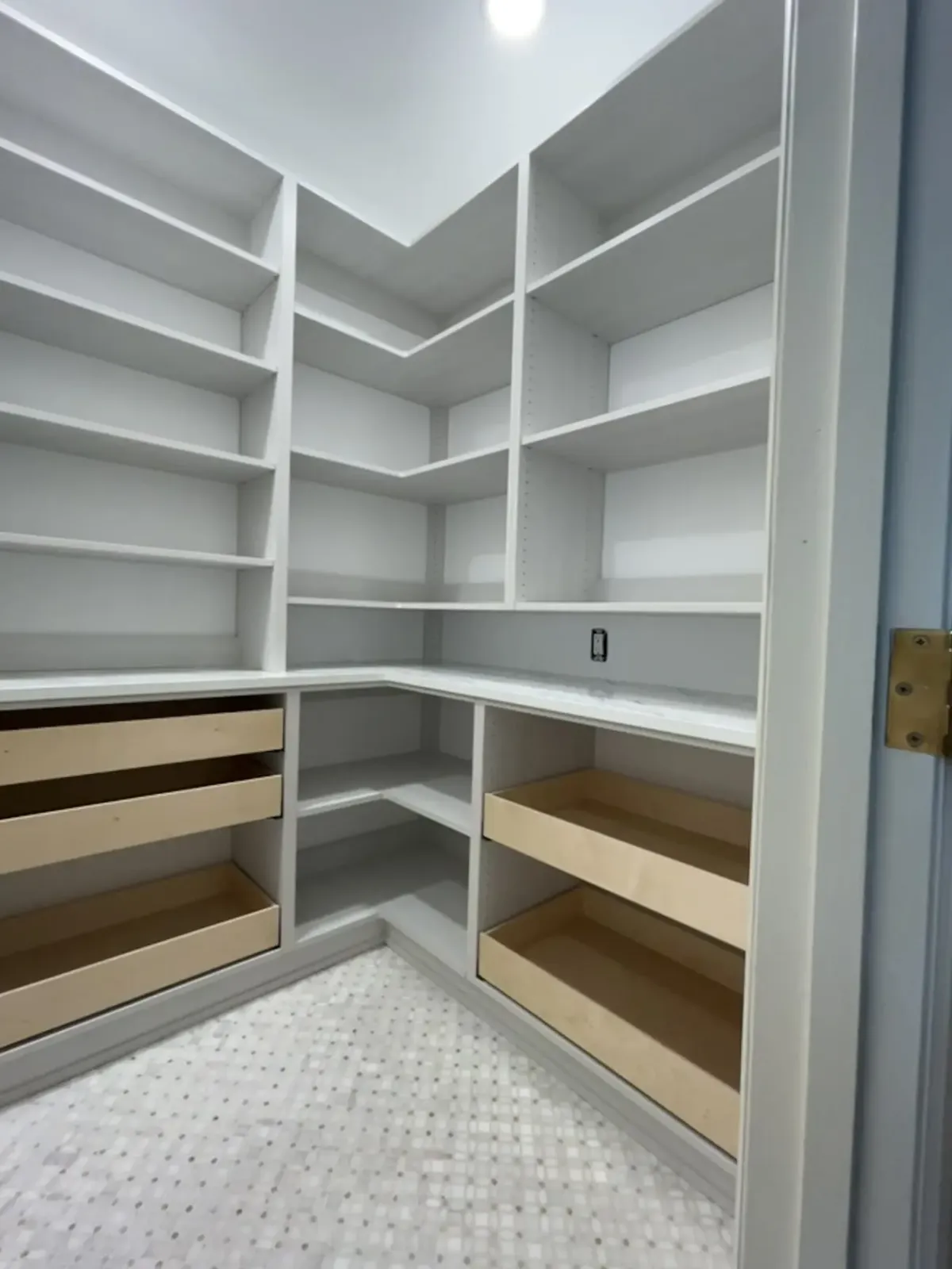 Corner pantry with pull-out wood drawers and open shelving over a mosaic tile floor