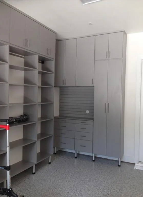 Garage storage wall combining open shelving, overhead cabinets and a slatwall panel above built-in drawers
